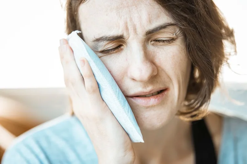 Illustrative photo of a person holding a cold compress against a swollen cheek